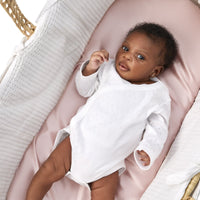 adorable little baby girl laying on a beddybyes blush pink Silk Moses Basket & Carrycot Fitted Sheet