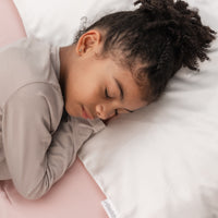 beautiful 7 yer old girl laying her head with curly hair on a pillow with a beddybyes snow white Silk Queen Pillowcase