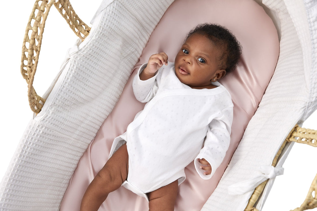 adorable little baby girl laying on a beddybyes blush pink Silk Moses Basket & Carrycot Fitted Sheet