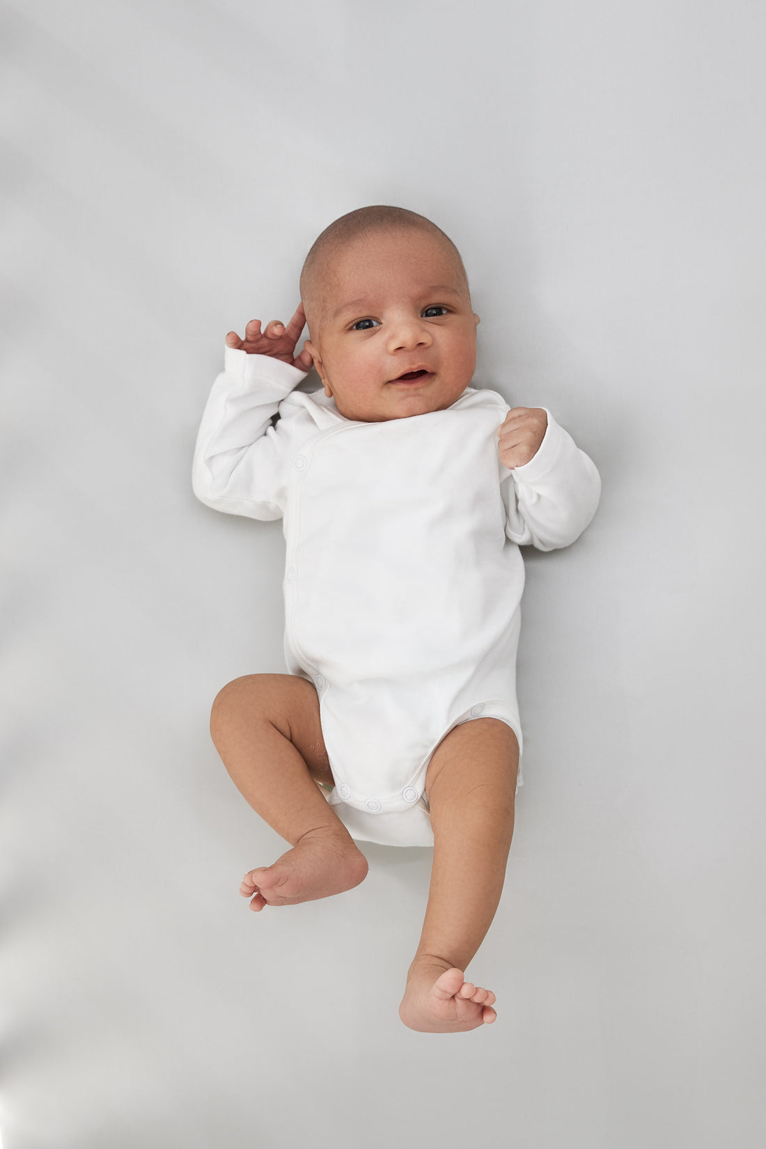 adorable little baby boy laying on a beddybyes silver grey Silk Cotbed Fitted Sheet