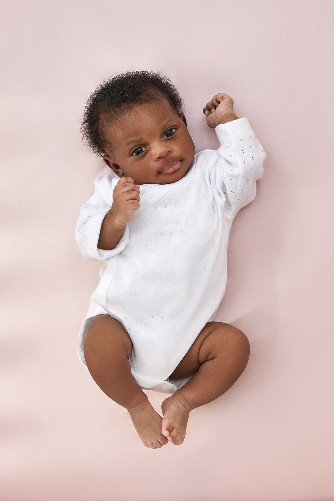 adorable little baby girl laying on a beddybyes rose pink Silk Cotbed Fitted Sheet