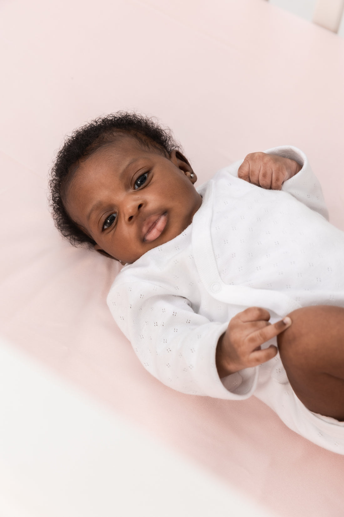 adorable little baby girl laying on a beddybyes rose pink Silk Cotbed Fitted Sheet