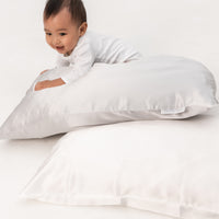 smiley toddler boy plays with a pillow covered with a beddybyes silver grey Silk Queen Pillowcase