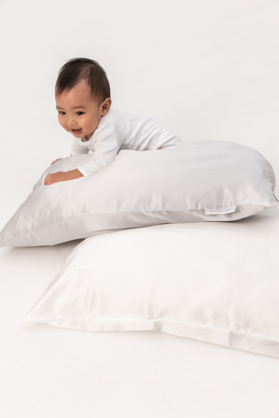 smiley toddler boy plays with a pillow covered with a beddybyes silver grey Silk Queen Pillowcase
