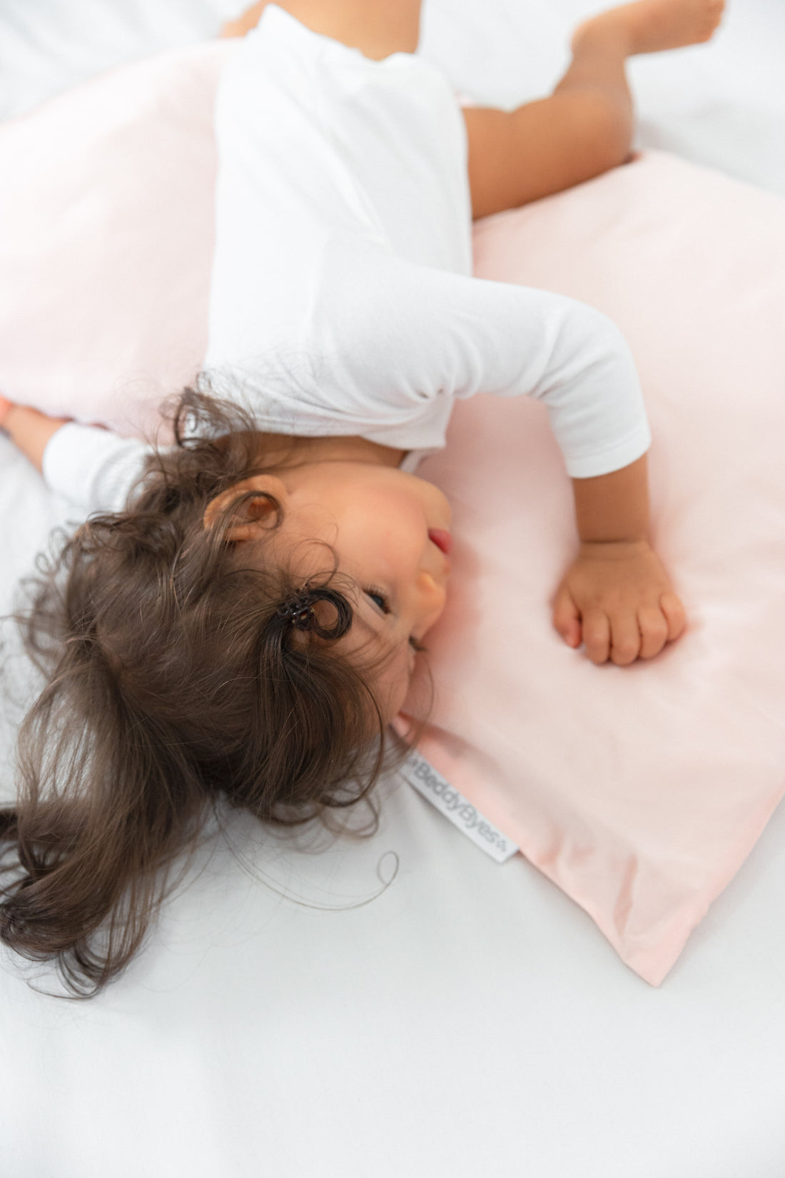 lovely toddler girl playing with a pillow covered with a beddybyes blush pink Silk Queen Pillowcase