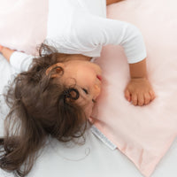 lovely toddler girl playing with a pillow covered with a beddybyes blush pink Silk Queen Pillowcase