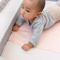 little toddler tummy time laying in a next to me bed with a beddybyes blush pink Silk Universal Travel Slip 