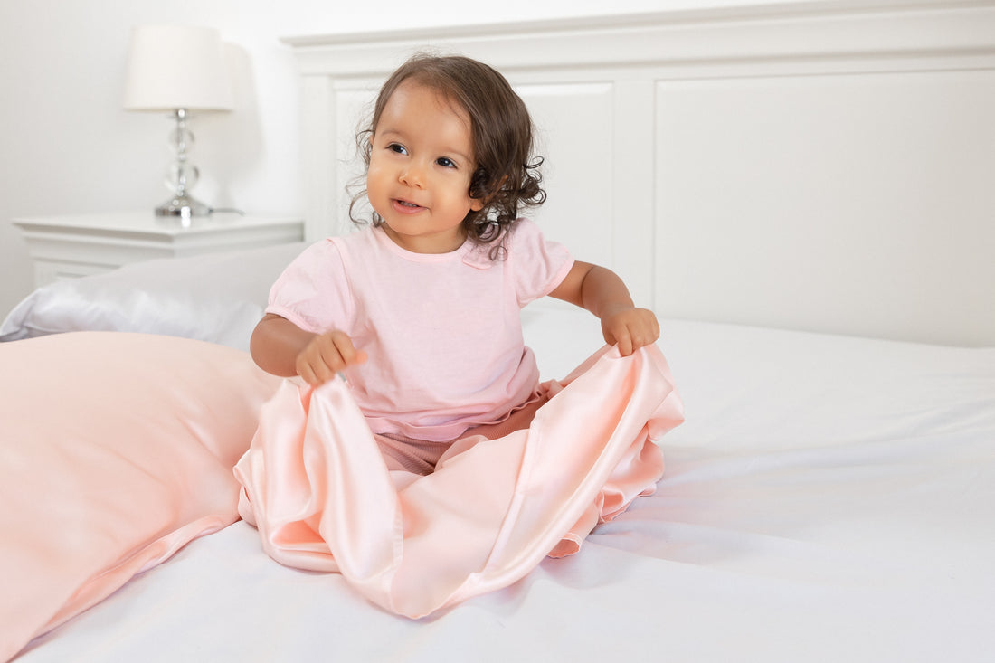 cute toddler girl holding a beddybyes blush pink Silk sheet