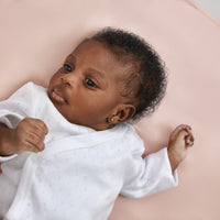 close up of gorgeous black baby girl laying on a beddybyes blush pink Silk Universal Travel Slip inside a cot bed